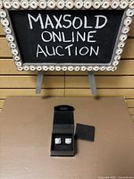 Cufflinks set in black display box with MaxSold Online Auction sign in background.