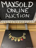 Full view of the gold tone chain bracelet with six heart charms showcasing different designs and colors against a black background.