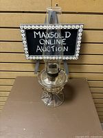 Full view of vintage heavy glass oil lamp with tall clear hurricane glass shade on a round, faceted base.