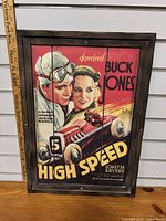 Framed vintage movie poster depicting 'High Speed' with Buck Jones, featuring two characters in racing attire and a race car, visible markings and vibrant colors.