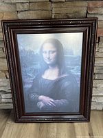 Front view of framed Mona Lisa artwork showing detailed dark wood carved frame and image of Mona Lisa portrait.