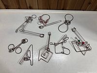 Eight metal brain teaser puzzles arranged on white surface, showing distinct wire shapes and rings.