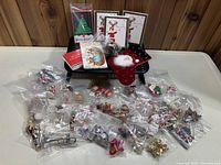 Large assortment of individually bagged Christmas ornaments laid out with cards and a plush stocking on a black display rack