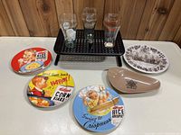Full lot showing Kellogg's plates, Coca-Cola glasses, mini bottle, Centennial ashtray and plate on display
