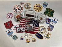 Lot showing all 4 vintage glass ashtrays surrounded by approximately 21 different vintage sew-on patches on an American flag background.
