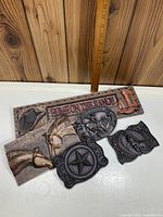 Photo of the five wall decor pieces laid out on a white surface, wooden background, with a ruler for size reference