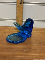 Front view of vibrant blue glass candle holder shaped like a bird, about 4 inches tall, sitting on a round base.