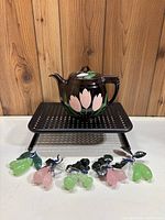 Canadian glazed pottery teapot with pink flower motif on dark brown glaze with 5 glass and wire fruit/berry decorative pieces in front.