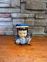 Front view of the painted ceramic head vase showing face, hat, and part of the dress