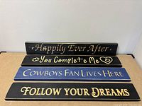 Four wooden signs arranged in stack showing text and colors broadly.