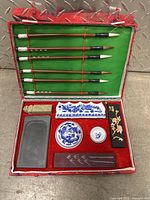 Complete traditional calligraphy set in open fabric-lined case showing brushes, ink holders, ink stone, and decorative pieces.