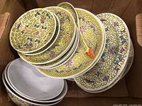 Yellow floral decorative plates stacked in a cardboard box