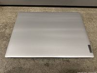 Closed silver Lenovo laptop showing Lenovo logo on top cover.