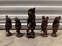 Front view of all five carved wood figurines arranged side by side
