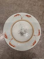 Underside view showing recessed foot ring, glaze pooling, and stylized red branch motifs around rim