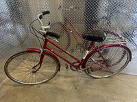 Full side view of the red Raleigh road bike showing frame, front and rear wheels, and handlebars.