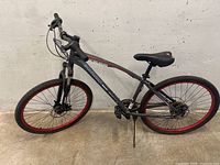 Side view of the entire Schwinn Onus mountain bike showing frame, wheels with red rims, pedals, and handlebar.
