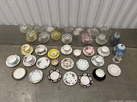Photo showing all 15 teacups and 15 saucers arranged in rows on the ground, each with individual decorative pattern and color.