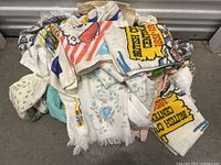 Pile of vintage tea towels with visible variety of patterns and colors including cartoon and floral prints.