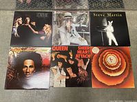 Photo showing six vinyl record album covers on a floor including Allen Toussaint Southern Nights, Elton John Greatest Hits, Steve Martin comedy album, Bob Marley Natty Dread, Queen Sheer Heart Attack, and Stevie Wonder Songs in the Key of Life.