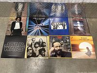 Eight vinyl record albums laid out flat on floor showing front covers.