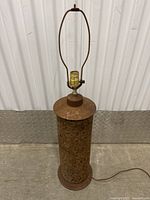 Full view of vintage cork lamp showing cylindrical cork body, metal base and lamp socket with harp attachment.