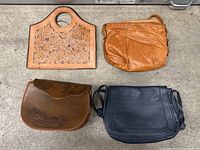 All four leather purses grouped together on floor showing overall lot condition and styles.