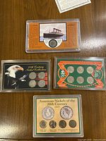 Top-down view of four nickel collections in plastic holders: Titanic commemorative coin, American Frontier Indian Head buffalo coin set, 20th century nickel collection, and a set with four different nickels including buffalo 1935.