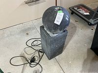 Full view of fountain assembly showing sphere on pedestal with pump cord visible