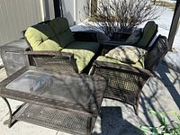 Overview of loveseat, two arm chairs, coffee table, cushions and deck box under covered area