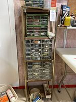 Full view of the metal storage shelf holding four drawer units stacked vertically with contents inside drawers visible.