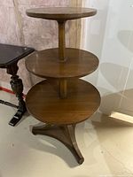 Full view of the three level round table showing wood veneer and walnut finish with pedestal construction and tri-legged base.