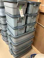 Stacked plastic Rubbermaid Roughneck totes in medium and small sizes, dusty and used condition.