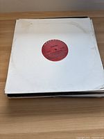 Stack of vinyl singles showing Mariah Carey record with red label in plain white paper sleeve with wear marks