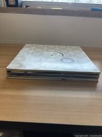 Side view showing stack of 10 vinyl record sleeves on a wooden surface