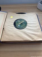Photo of a single antique 78 RPM record with Columbia label in brown paper sleeve, on wooden table