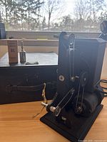 Photo showing Kodascope Eight Model 50 projector with original oil bottle and box on wooden surface