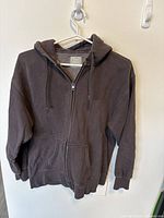 Front view of dark gray zip-up Aritzia TNA Boyfriend hoodie showing the hood, pockets, and zipper