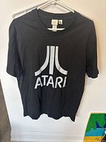 Front view of black Atari T-shirt with white logo and text