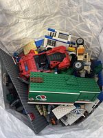 Bag of Lego pieces showing red Ferrari car and Batman car with assorted loose bricks