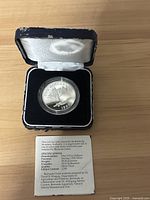 Front view of coin in case with informative certificate showing specifications and edition limit.