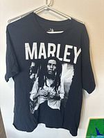 Front view of the black XL T-shirt featuring a large white graphic of Bob Marley with the text 'MARLEY' above his image.