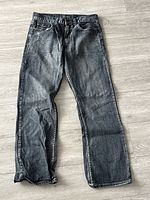 Full view of black washed denim bootcut jeans laid flat showing overall appearance and condition.
