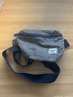 Image showing side pouch bag with stripe design, navy zipper, and adjustable strap