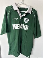 Front view of green Ireland rugby jersey with white collar, showing 'IRELAND' text, Lansdowne logo, and shamrock crest.
