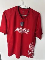 Front view of red Korean Football Association soccer jersey showing KFA badge, Korea text logo, and white tiger graphic detail.
