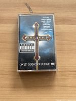 Front view of cassette tape case with album art showing gold cross and parental advisory