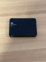 Top view of WD My Passport Ultra 2TB external hard drive on a wooden surface showing front logo and dimpled pattern.