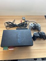 Top view of PlayStation 2 slim console showing controllers and cables.