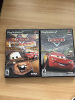 Front view of two PlayStation 2 game cases featuring Cars video games.